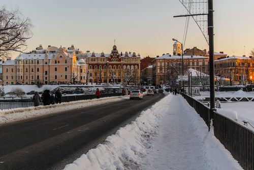 Free Charming winter cityscape with snow-covered streets and historic architecture at sunset. Stock Photo