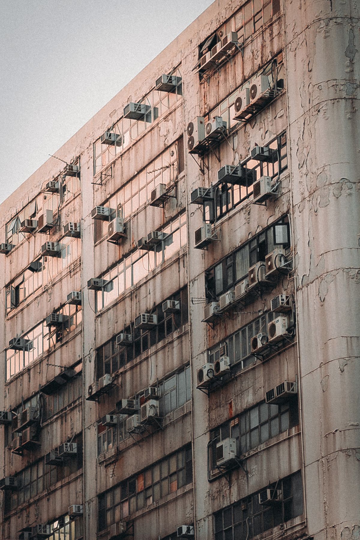 A weathered residential building in Hong Kong covered with air conditioning units