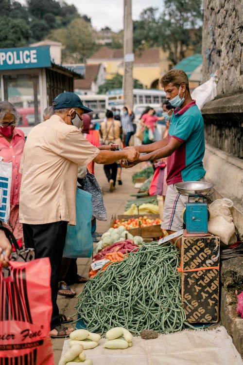 Man in Green and Red Shirt Selling Vegetables