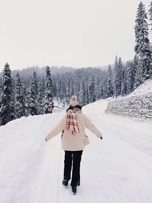 Back View of a Woman in Winter Clothes Walking on the Snow