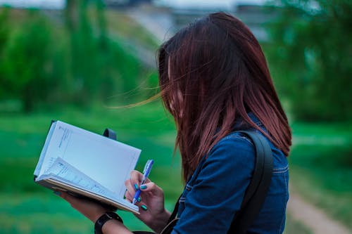 Close-Up Photography of a Person Writing on Notebook