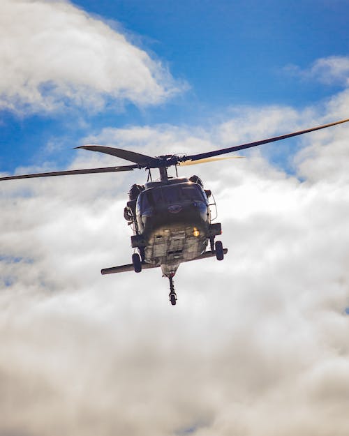 Photograph of a Black Helicopter Near White Clouds