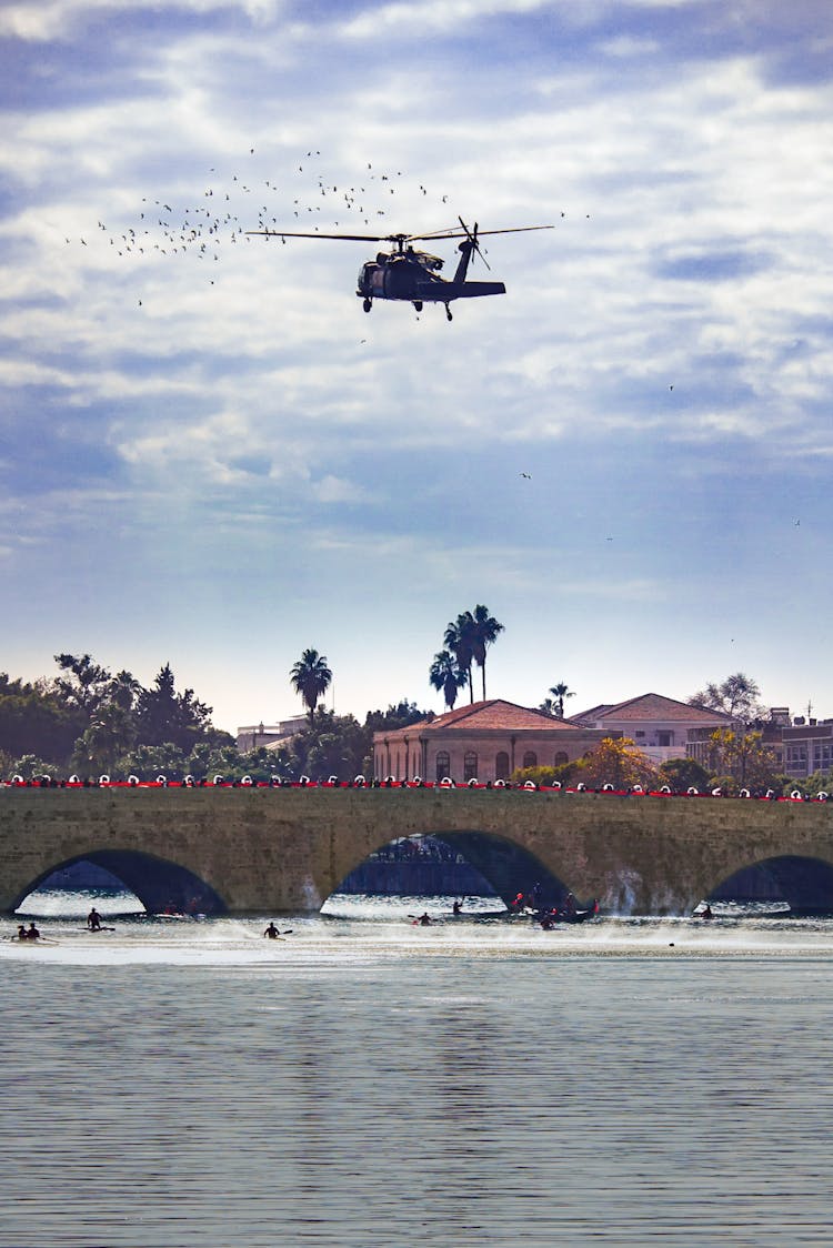 Black Helicopter Flying Over Body Of Water