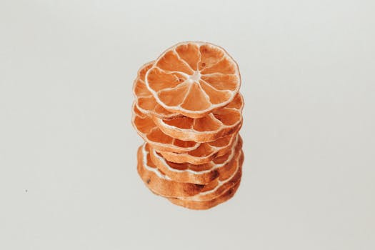 Close-up of neatly stacked dried citrus slices on a white surface. Perfect for culinary or organic themes.