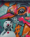 White Snowman with Scarf and Hat Beside Illustrated Bird on the Wall