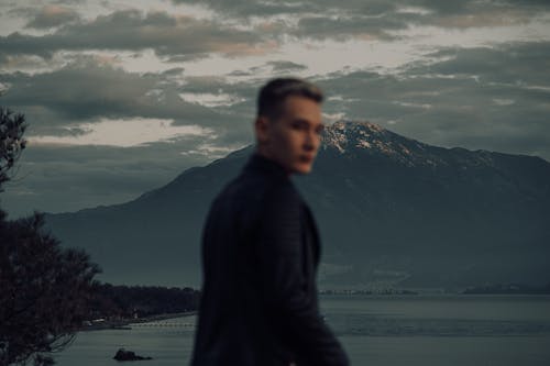 Free Man in Black Jacket Standing Near Body of Water Stock Photo