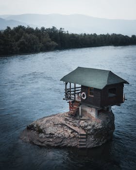Floating house atop a rock on Serbia's Drina River at daytime, an iconic view.