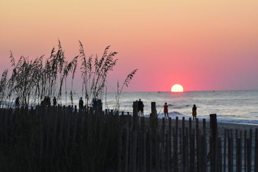 A peaceful sunrise at Myrtle Beach with silhouettes of people on the shoreline creating a tranquil scene.