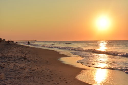 Foto gratuita de personas en la playa durante el amanecer