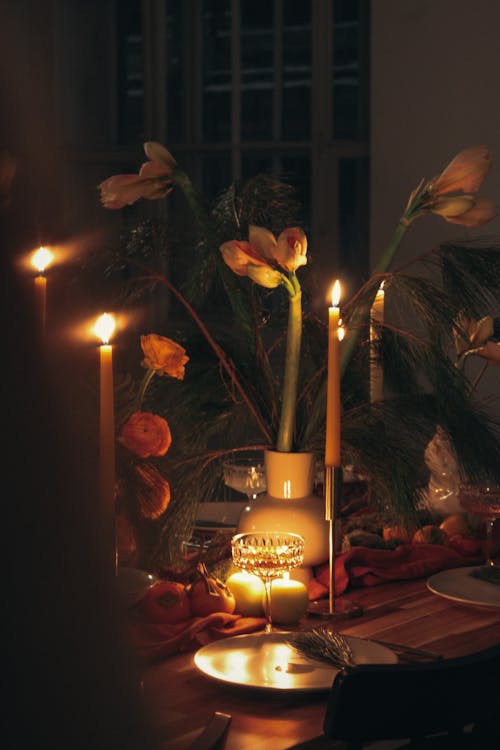 Lighted Candles on Table With White and Pink Flowers on White Ceramic Flower Vase