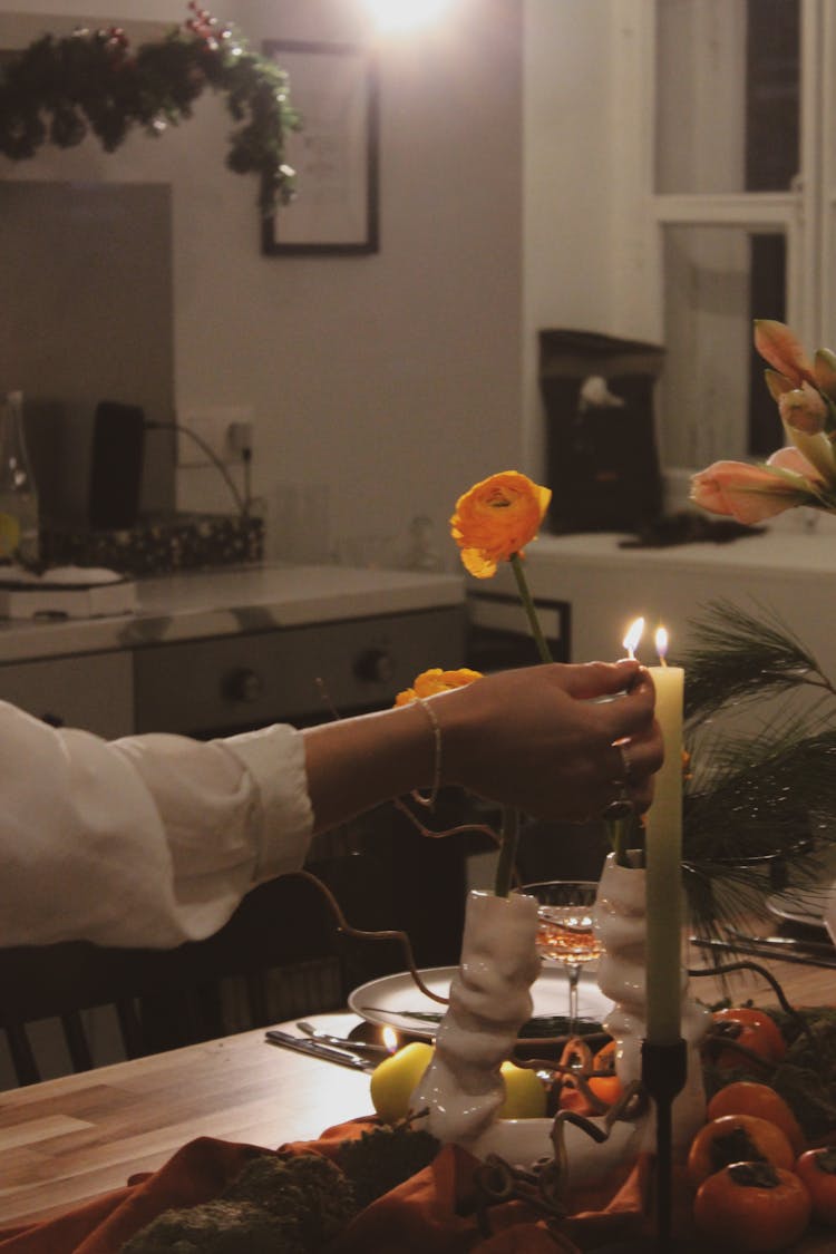 A Person In White Long Sleeves Lightning The Candle On A Stand 