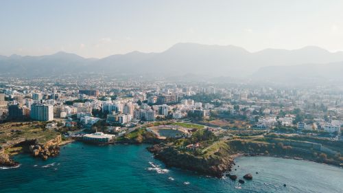 Free A stunning aerial view of a coastal city with mountains and clear blue sea, showcasing urban and natural beauty. Stock Photo