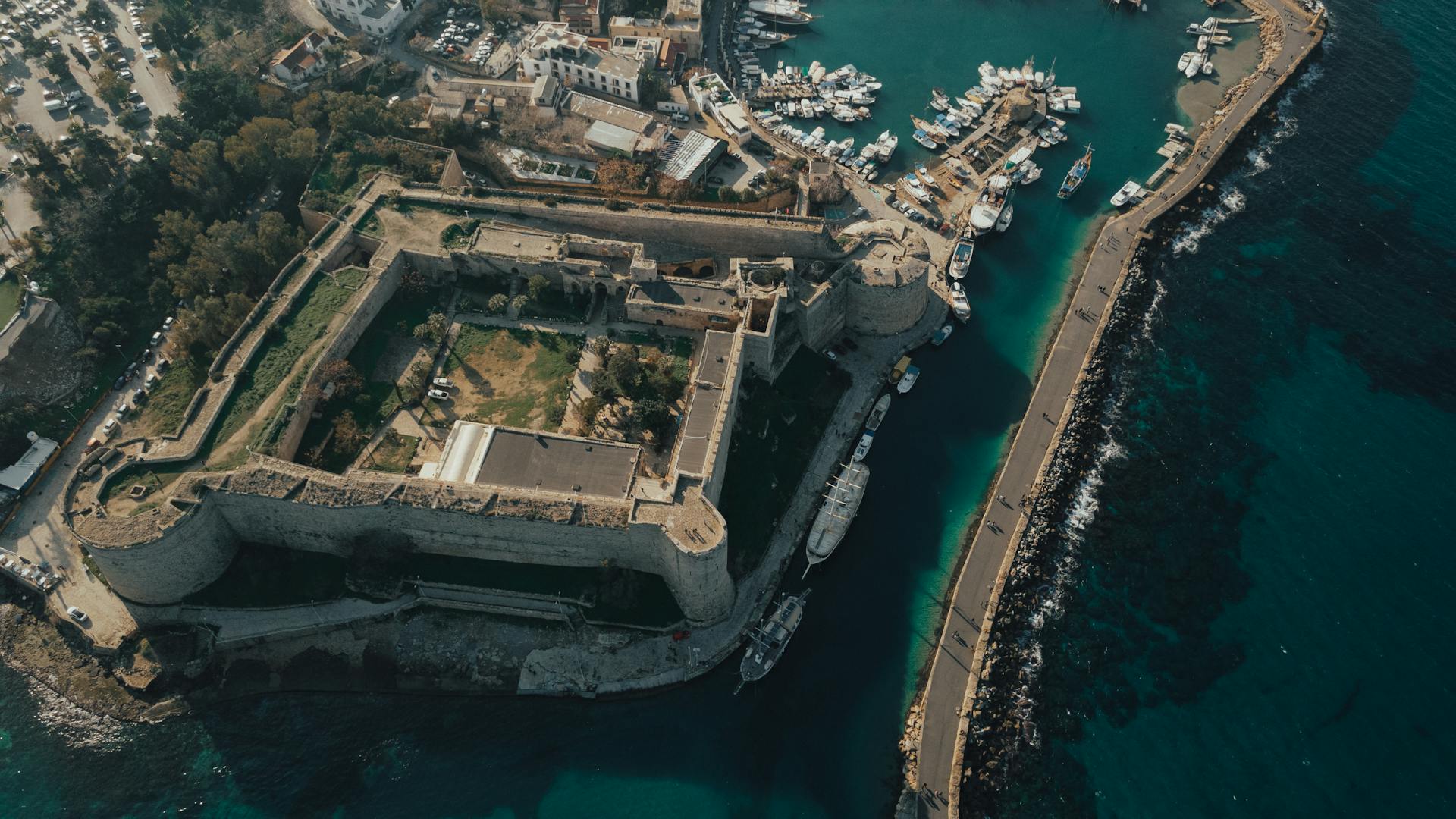 Explore a stunning aerial view of a historic fortress by the sea, capturing local landmarks.