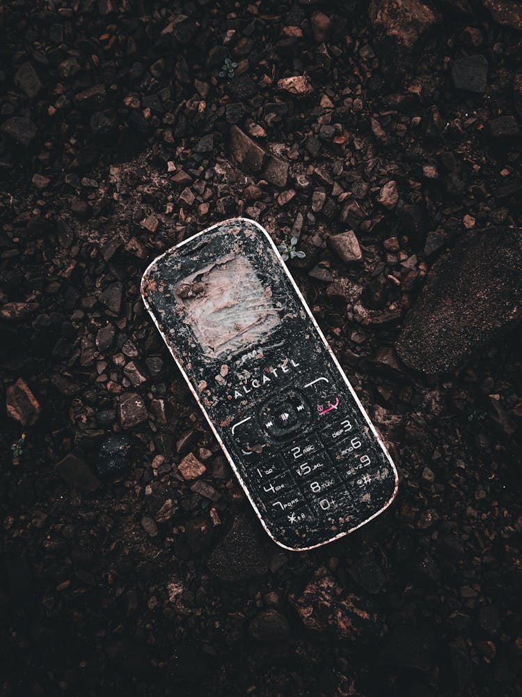 Dirty Black Keypad Cellphone On Rocky Ground 