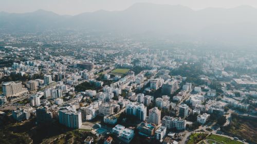 Free Aerial view of a foggy cityscape with buildings and mountains in the distance. Stock Photo