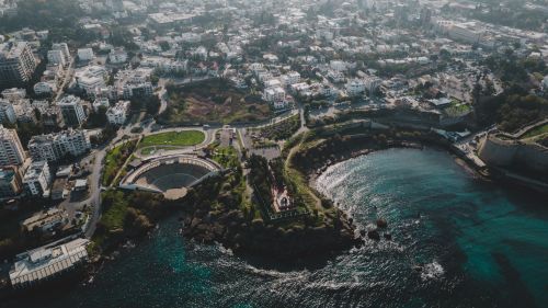 Free A stunning aerial photo capturing the coastal cityscape with an ancient amphitheater and blue sea. Stock Photo