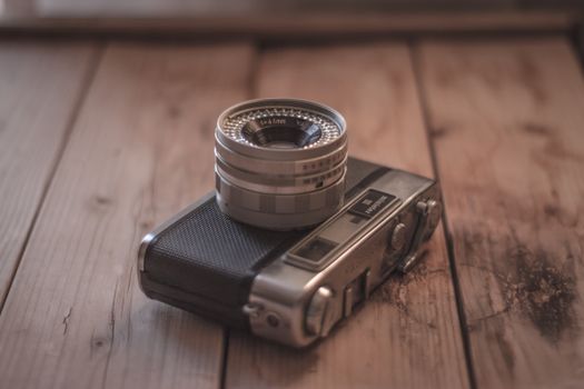 Close-up of an analog vintage camera on a rustic wooden surface.