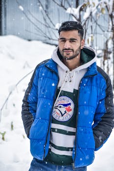 A man smiling in a blue jacket outside on a snowy winter day.