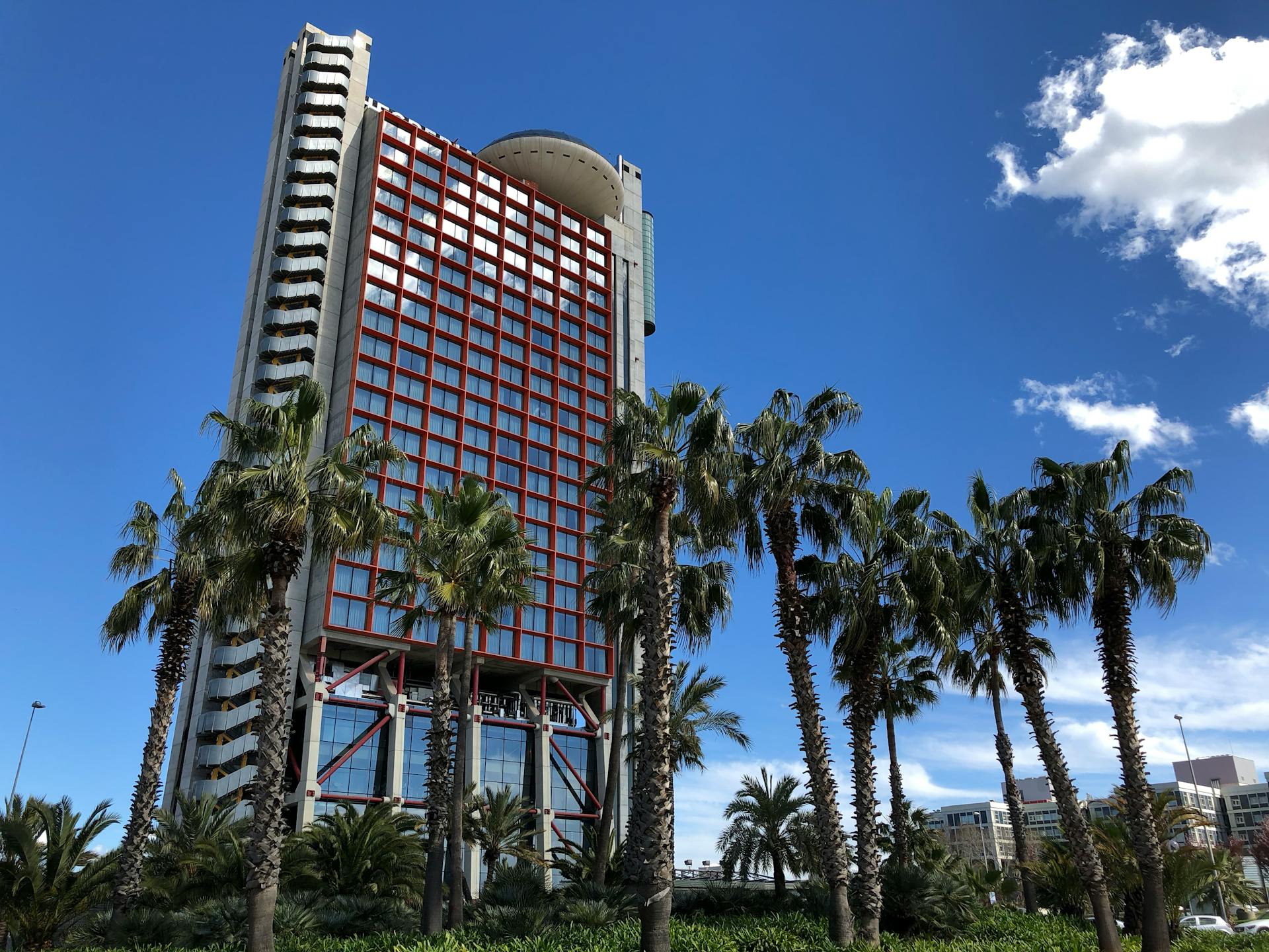 The Hyatt Regency Barcelona Tower stands tall amid lush palm trees in L'Hospitalet, Spain.