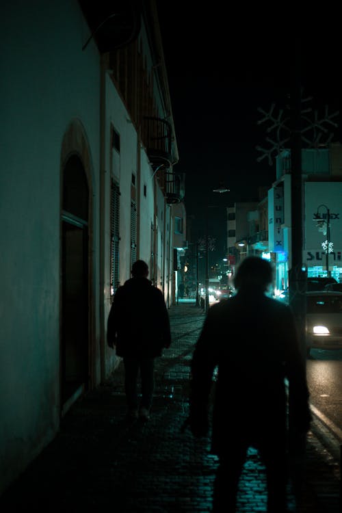 Silhouette of People Walking on Sidewalk during Night Time