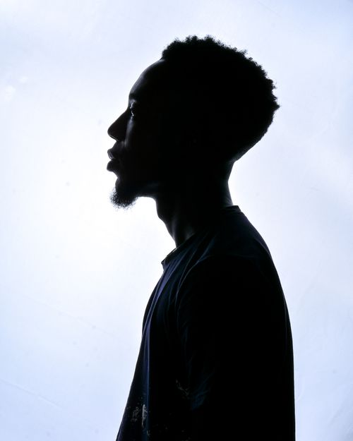 Free Silhouette of a man in profile with a backlit effect indoors, creating artistic shadow and contrast. Stock Photo