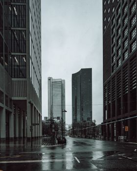A rainy day in a modern city with high-rise buildings and a wet street, showcasing urban architecture.
