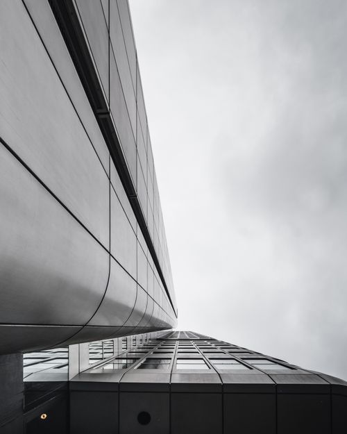 Free Low angle view of a modern skyscraper with an industrial facade against a cloudy sky. Stock Photo