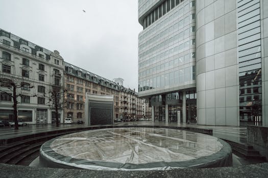 View of modern and historical buildings in a city plaza on a gloomy day.
