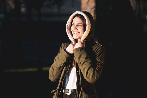 Free Smiling woman in a hoodie jacket enjoying sunlight outdoors in Reno. Stock Photo