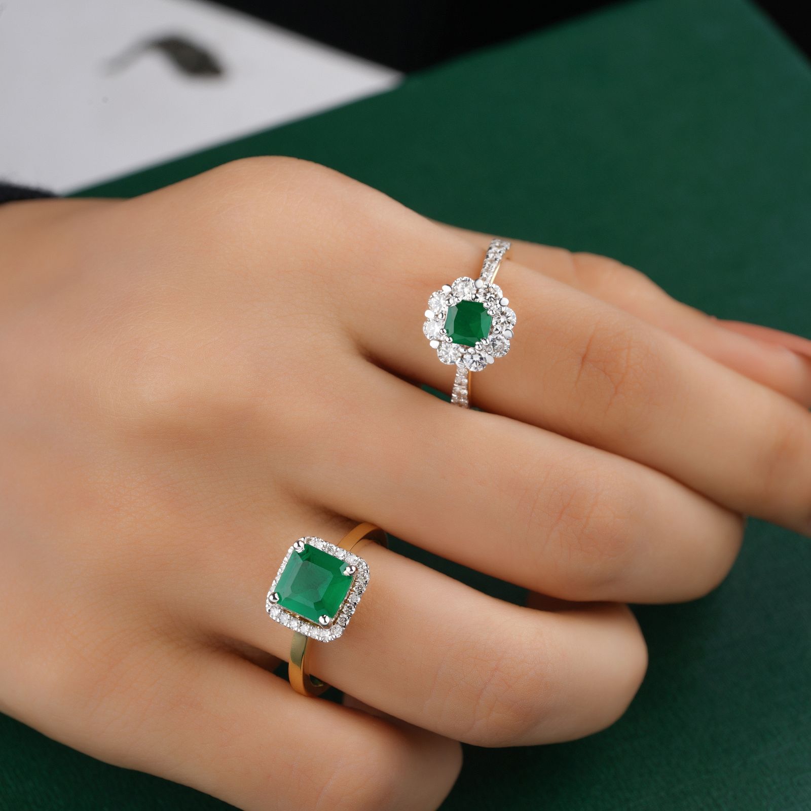 A hand wearing an emerald and diamond ring