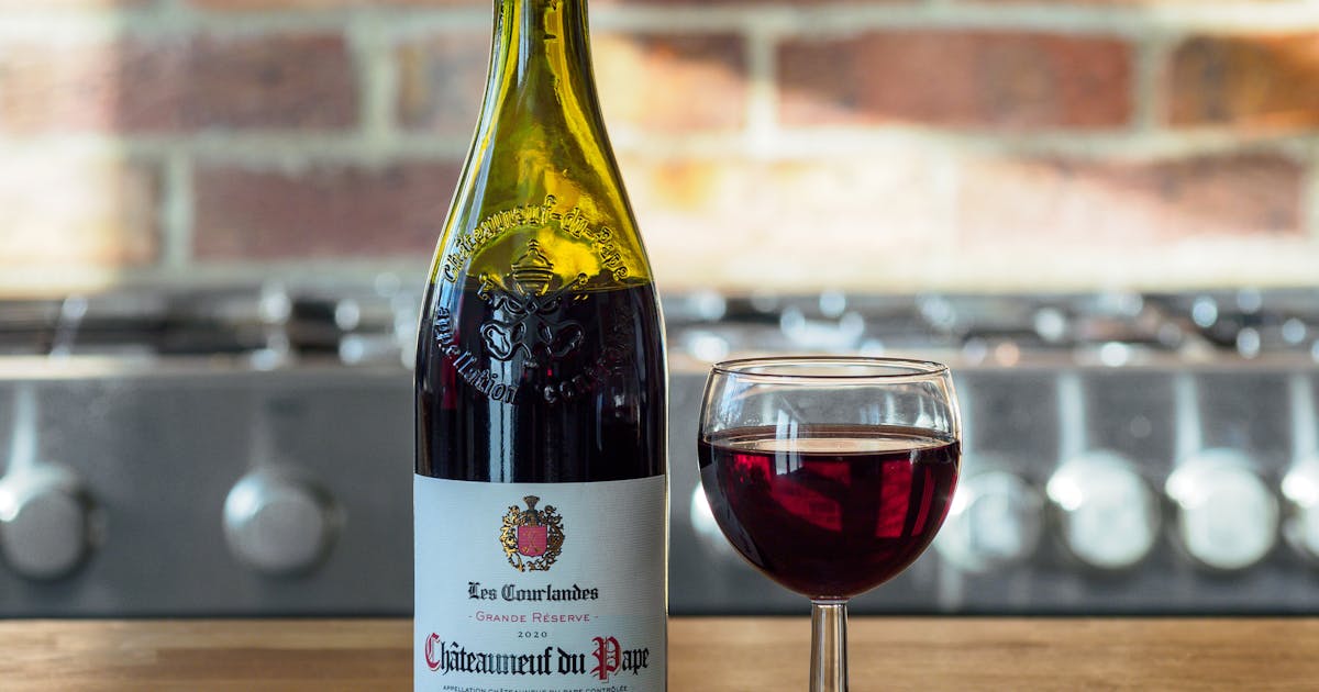 Une personne dégustant un verre de vin avec un plat gastronomique.