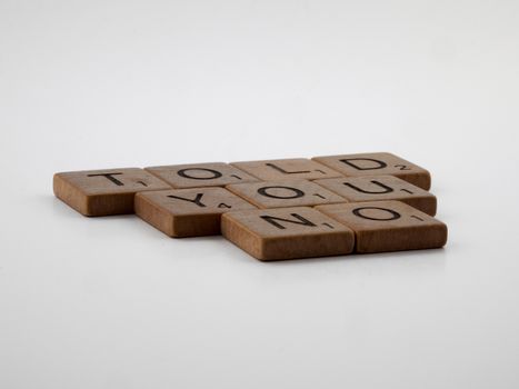 Scrabble tiles arranged to spell 'TOLD YOU NO', placed on a white surface.