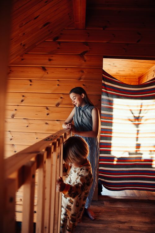 Free A mother and her child enjoy a moment inside a wooden cabin with warm lighting. Stock Photo
