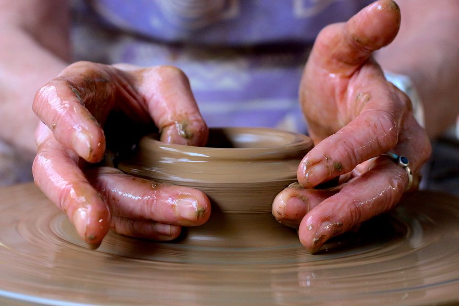 Hands shaping clay on spinning pottery wheel during workshop session