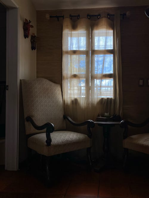 Wooden Padded Armchair Beside a Wooden Framed Glass Window