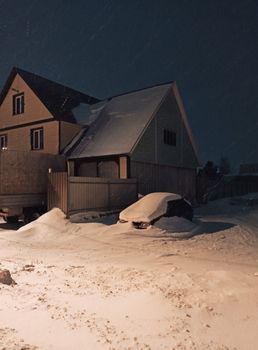 A car and house blanketed in snow during a cold winter night in Berdsk, Russia.