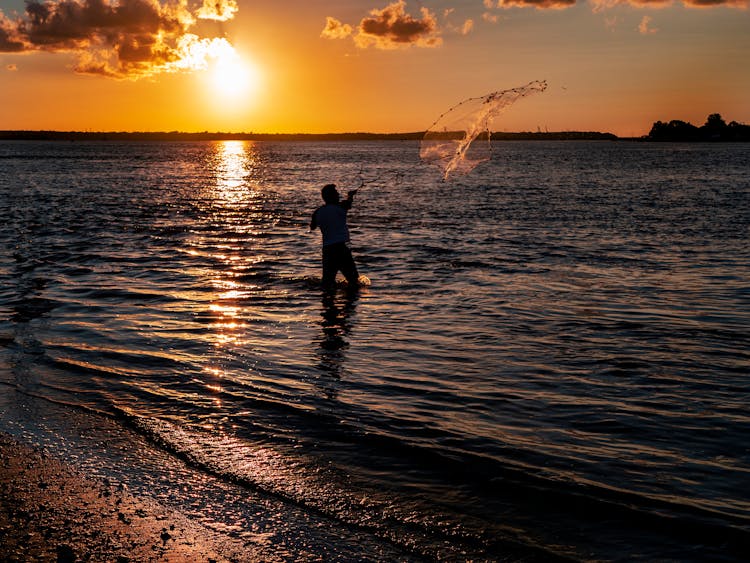 Silhouette Of Man Throwing A Fishing Net