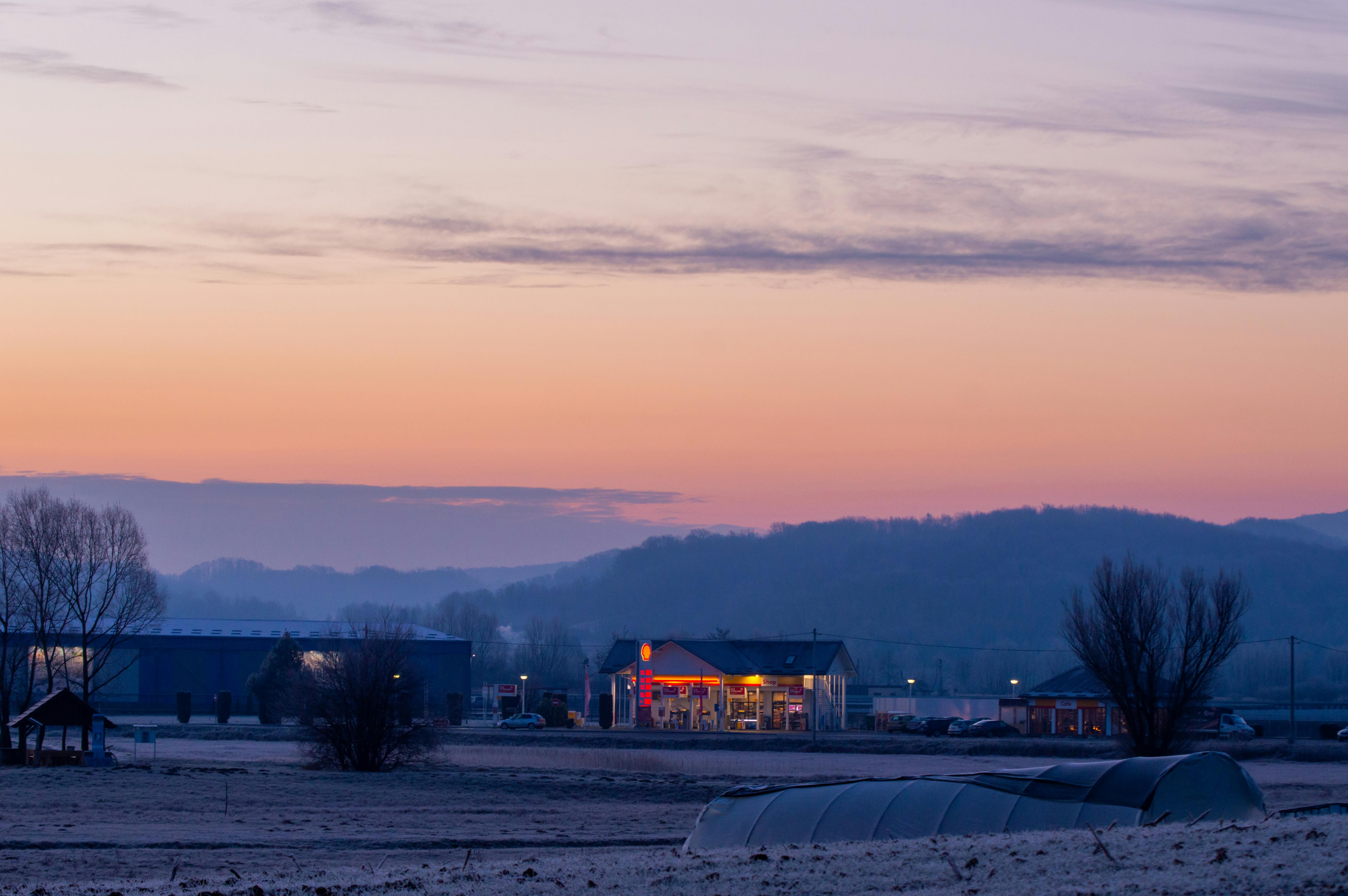 Illuminated Gas Station near Mountains during Sunset · Free Stock Photo