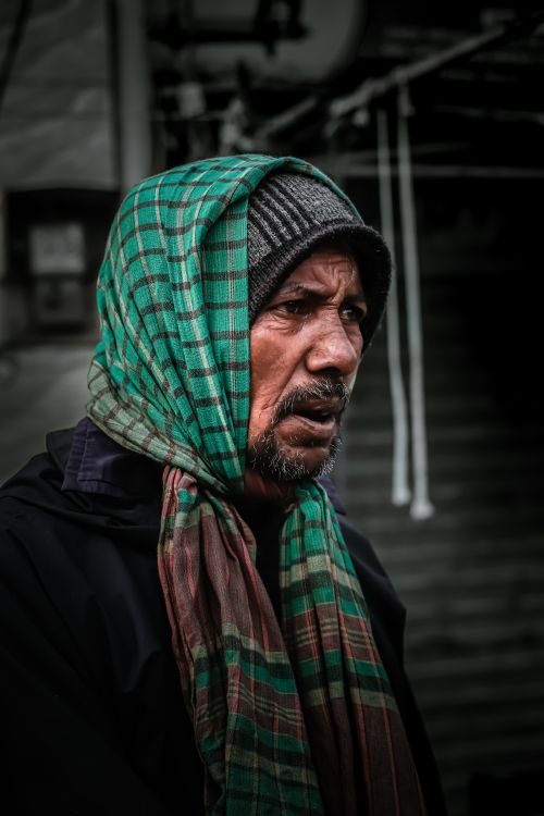 Free Emotional portrait of a man in Dhaka wearing a green and red checkered headscarf. Stock Photo