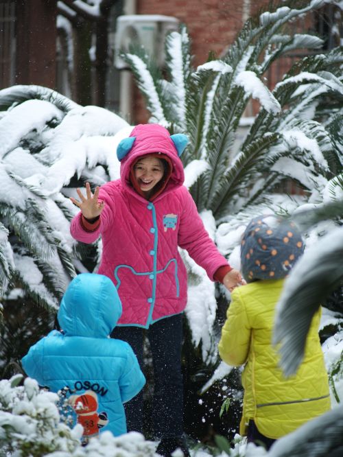 Free Three children enjoy a playful day in the snow among palm trees, dressed in colorful winter clothes. Stock Photo