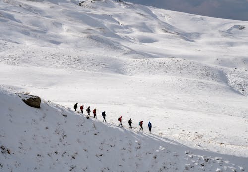 People Trekking on Snow Covered Mountain