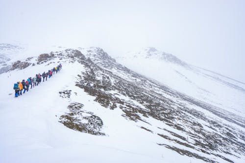 Hikers Walking on a Snow Covered Mountain