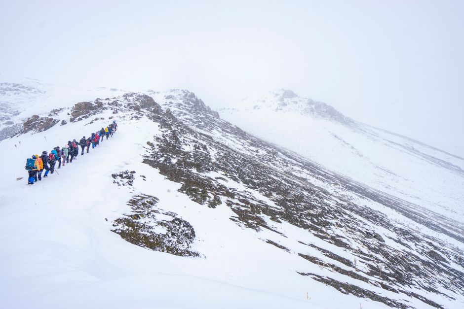 A group of hikers traversing a snowy mountain landscape in Van, Türkiye.