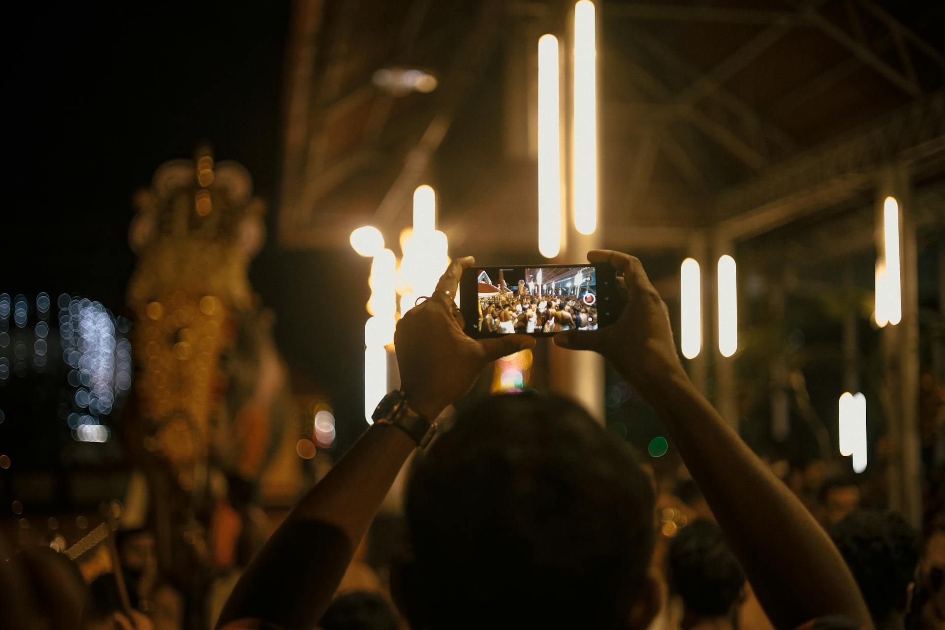 Festival attendees in India use smartphones to capture vibrant night celebrations.