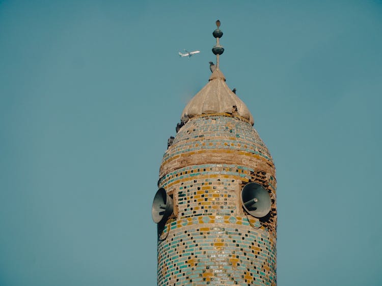 Airplane Passing Near The Brown Concrete Tower 