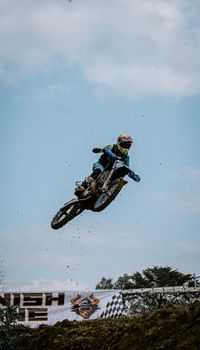 Exciting image capturing a motocross rider in mid-air against a clear blue sky, showcasing extreme sports action.