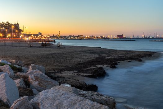 A peaceful beach view with city lights at dusk, capturing the serene waterfront and urban skyline.