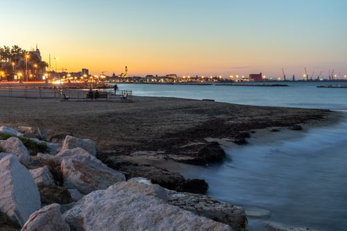 Free A peaceful beach view with city lights at dusk, capturing the serene waterfront and urban skyline. Stock Photo