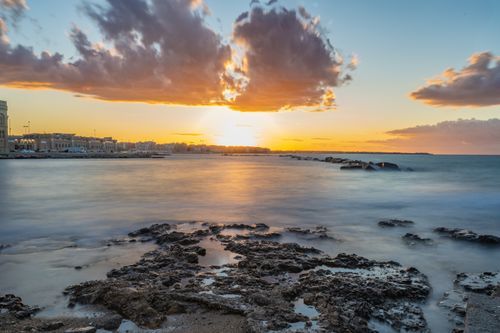 Free Stunning seaside cityscape captured at sunrise with vibrant skies and calm waters. Stock Photo