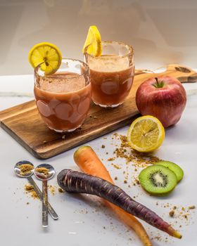 Colorful fruit and vegetable smoothie with healthy ingredients on a wooden board.